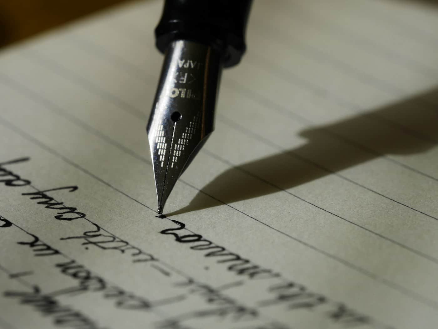 A fountain pen resting on handwritten pages, close up — the signing of a will