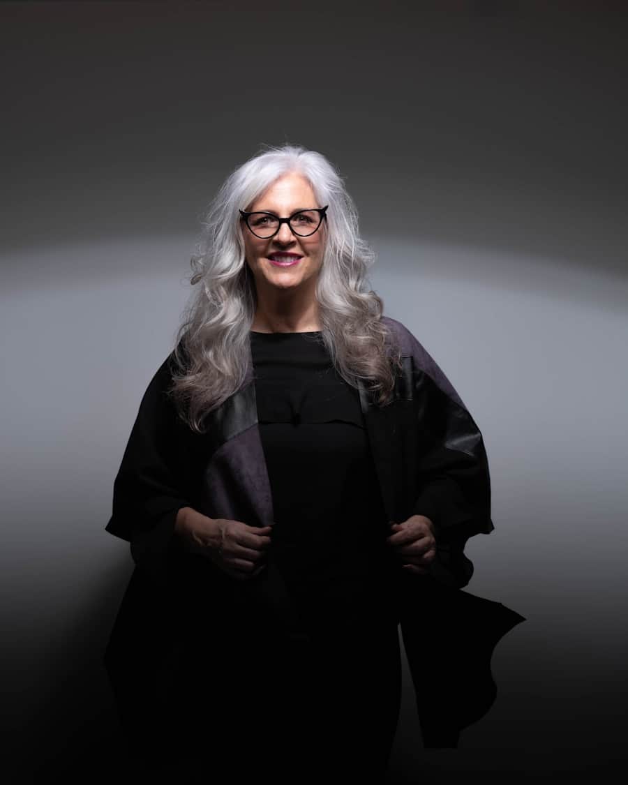 Eleanor Merritt, partner at Merritt & Bell — silver-haired, in glasses and dark dress, photographed against a plain dark ground